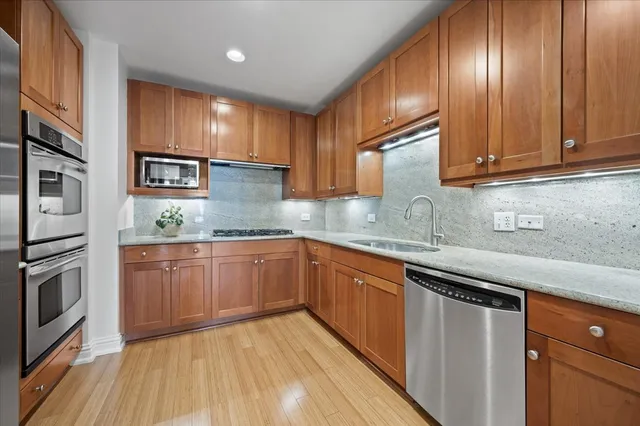 a kitchen with granite countertop wooden cabinets stainless steel appliances and a sink