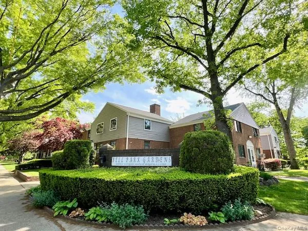 a front view of a house with a yard and large trees