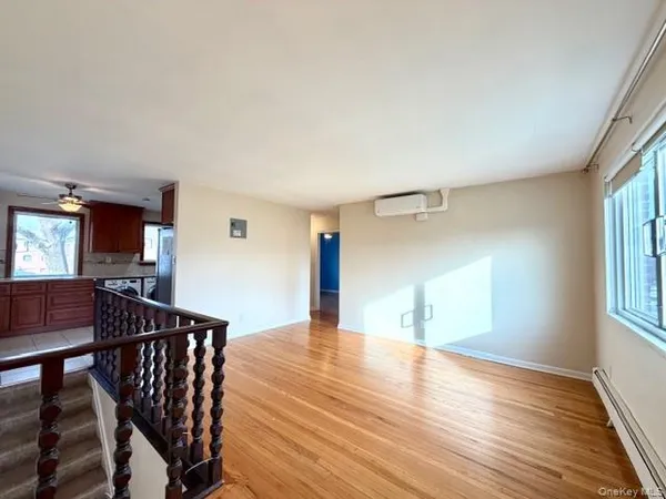 a view of an empty room with window and wooden floor
