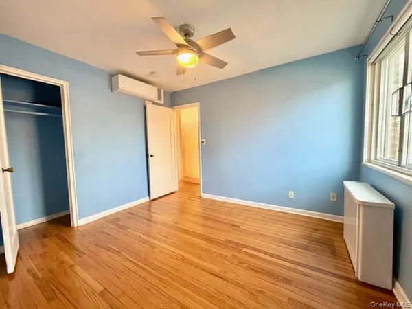 a view of an empty room with window and wooden floor