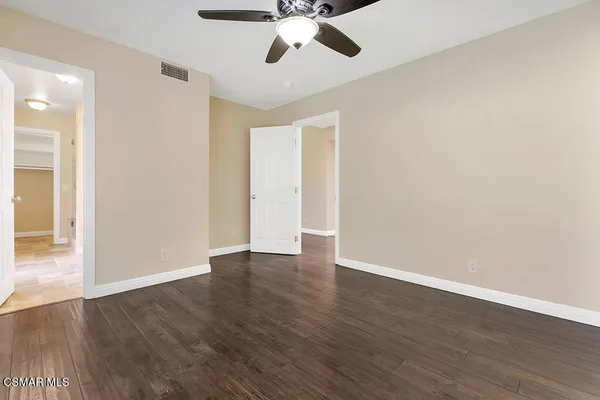 a view of an empty room with wooden floor a fireplace and a window