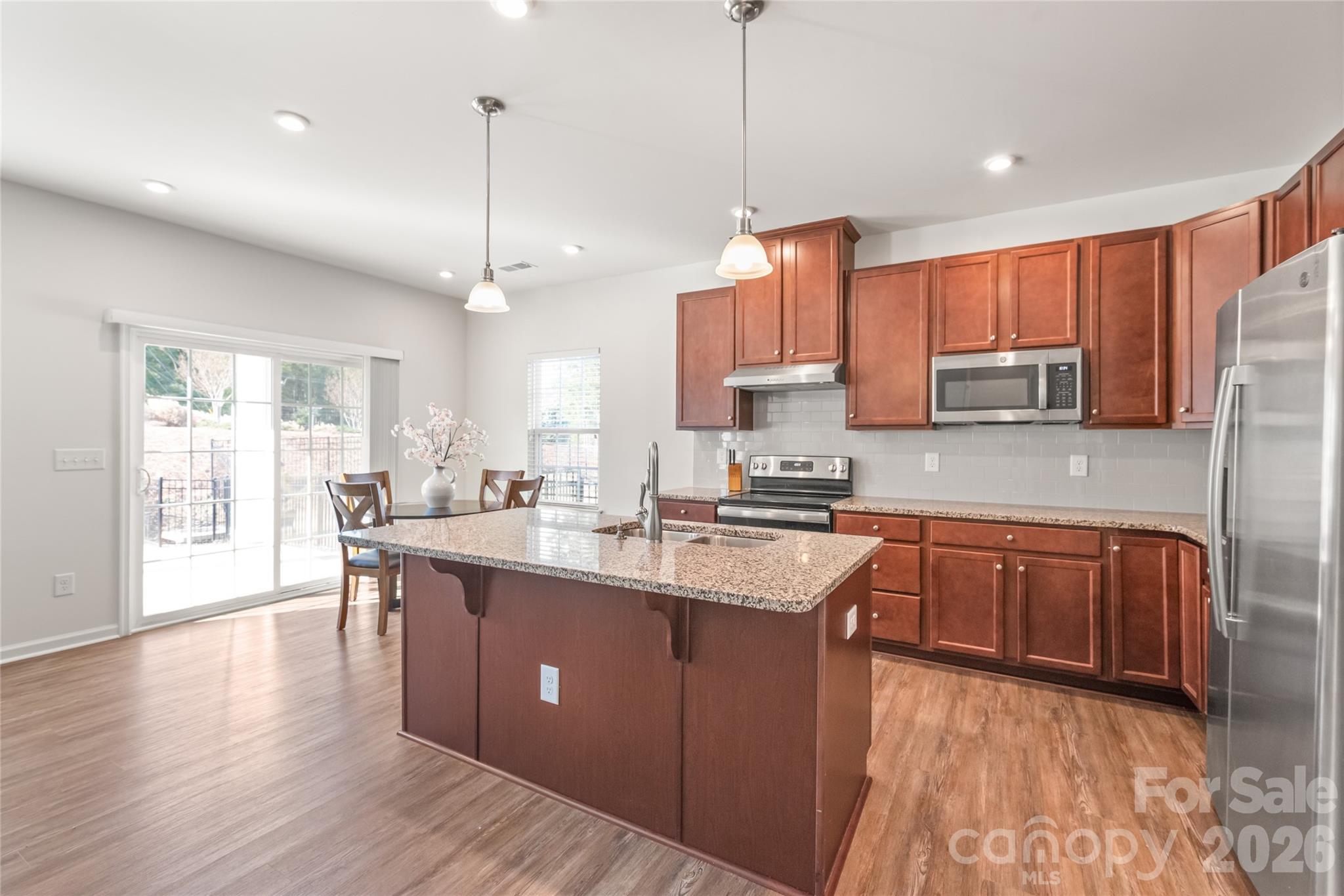 1960 Slippery Rock Lane Monroe, NC 28112 - Photo 5 of 32 a kitchen with stainless steel appliances granite countertop a sink a stove a refrigerator cabinets and wooden floor
