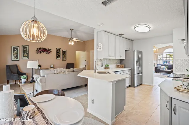 a large white kitchen with a white countertops a stove and a chandelier