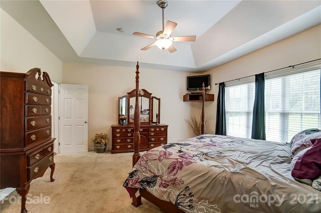 9180 Meadowood Road Mount Pleasant, NC 28124 - Photo 23 of 37 a bedroom with a bed a dresser and a chandelier