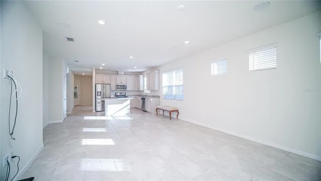 a large kitchen with stainless steel appliances granite countertop a stove a sink a refrigerator and white cabinets