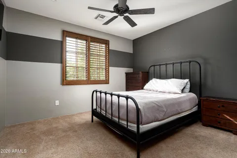 a bed sitting in a bedroom next to a window and a chandelier