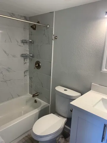 a white toilet and tub sitting next to a bathroom sink