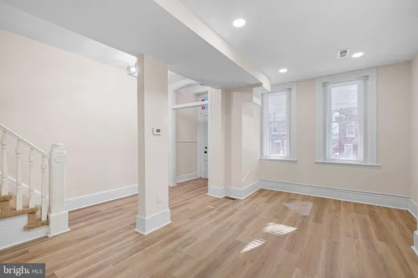 an empty room with wooden floor and windows