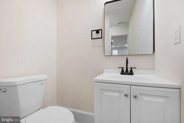 a bathroom with a toilet sink vanity and mirror