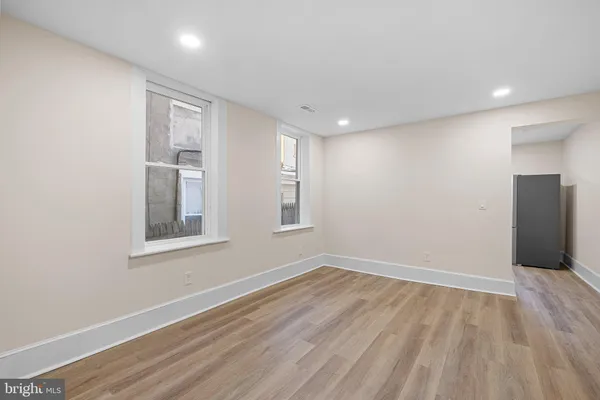 a view of an empty room with wooden floor and a window