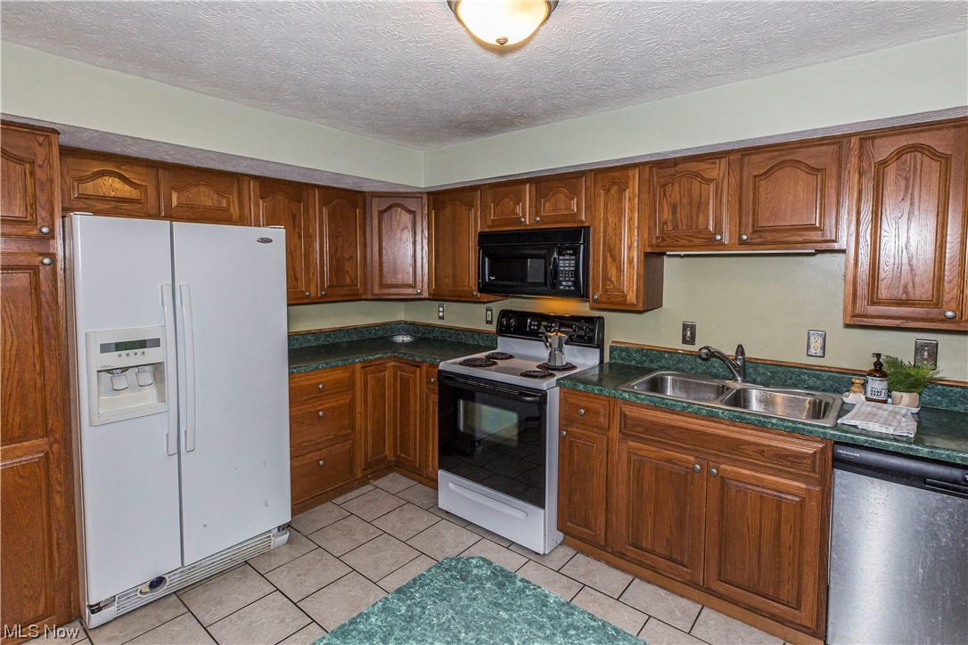 3755 North Santom Road Stow, OH 44224 - Photo 13 of 23 Kitchen with light tile floors, sink, white appliances, and a textured ceiling