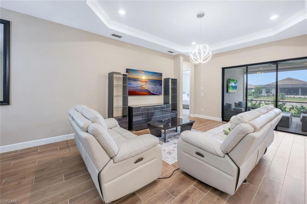 8448 Rosa Court Naples, FL 34114 - Photo 6 of 24 Living area featuring wood-finish flooring, crown molding, recessed lighting, and a modern pendant light fixture