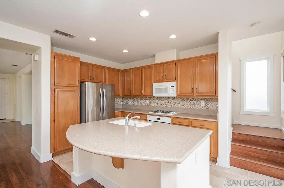1818 Sheep Ranch Loop Chula Vista, CA 91913 - Photo 13 of 40 a kitchen with stainless steel appliances granite countertop a sink a refrigerator and a stove with wooden floor