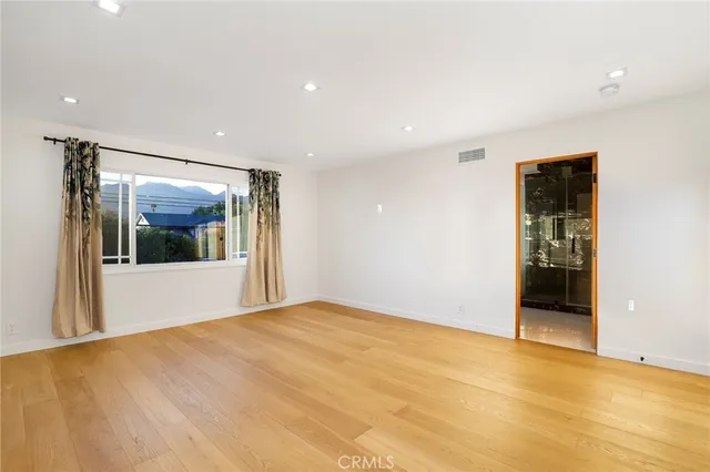 a view of an empty room with window and wooden floor