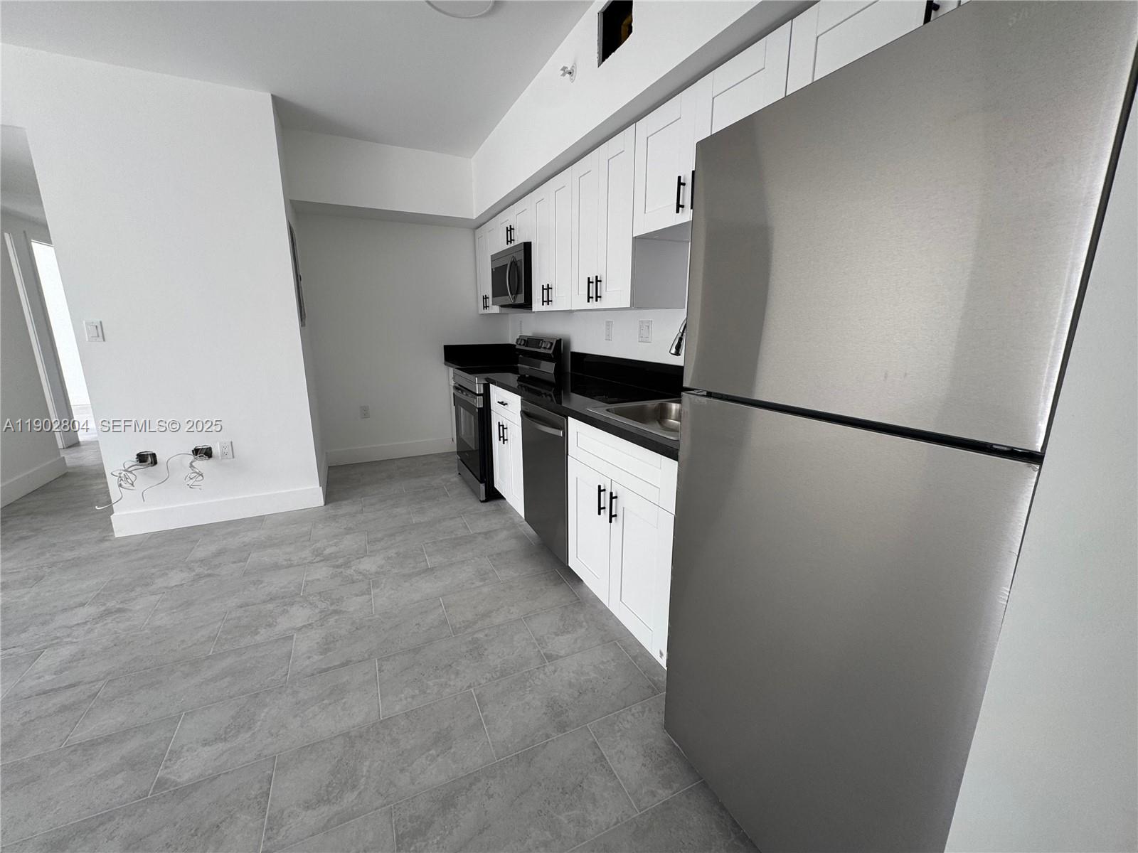 147 Northwest 59th Street, Unit 206 Miami, FL 33127 - Photo 11 of 11 a kitchen with refrigerator and white cabinets