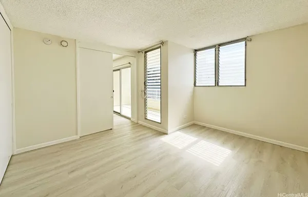 an empty room with wooden floor and windows