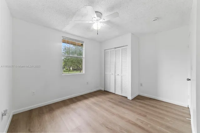 an empty room with wooden floor and ceiling fan