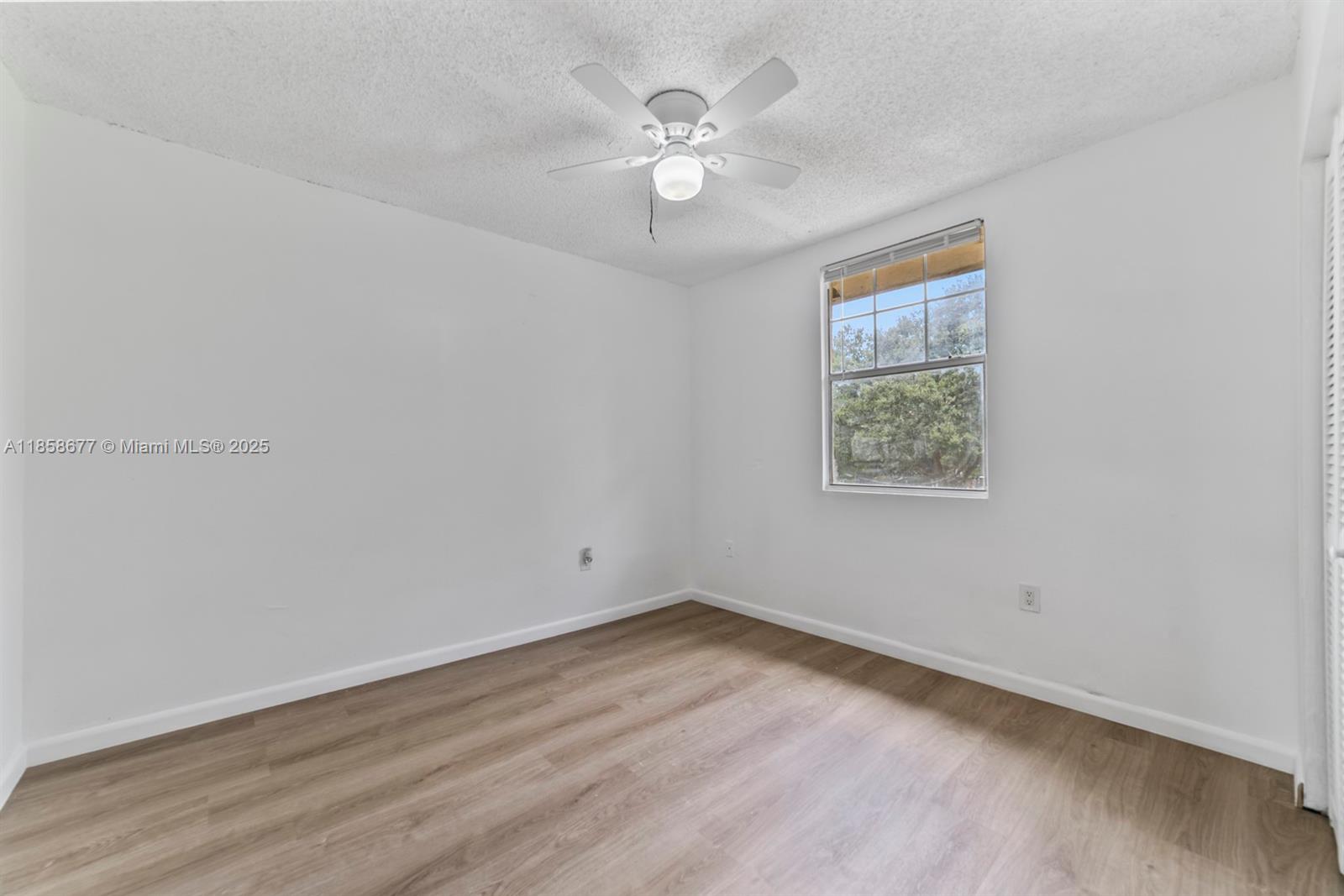 3358 Northwest 198th Terrace Miami Gardens, FL 33056 - Photo 25 of 26 an empty room with wooden floor and ceiling fan