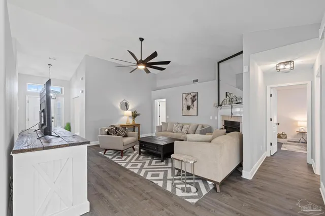 a kitchen with stainless steel appliances granite countertop a stove top oven a sink a refrigerator and white cabinets with wooden floor