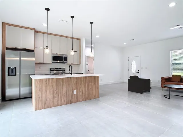 a kitchen with stainless steel appliances a stove a refrigerator a sink a counter top space and cabinets