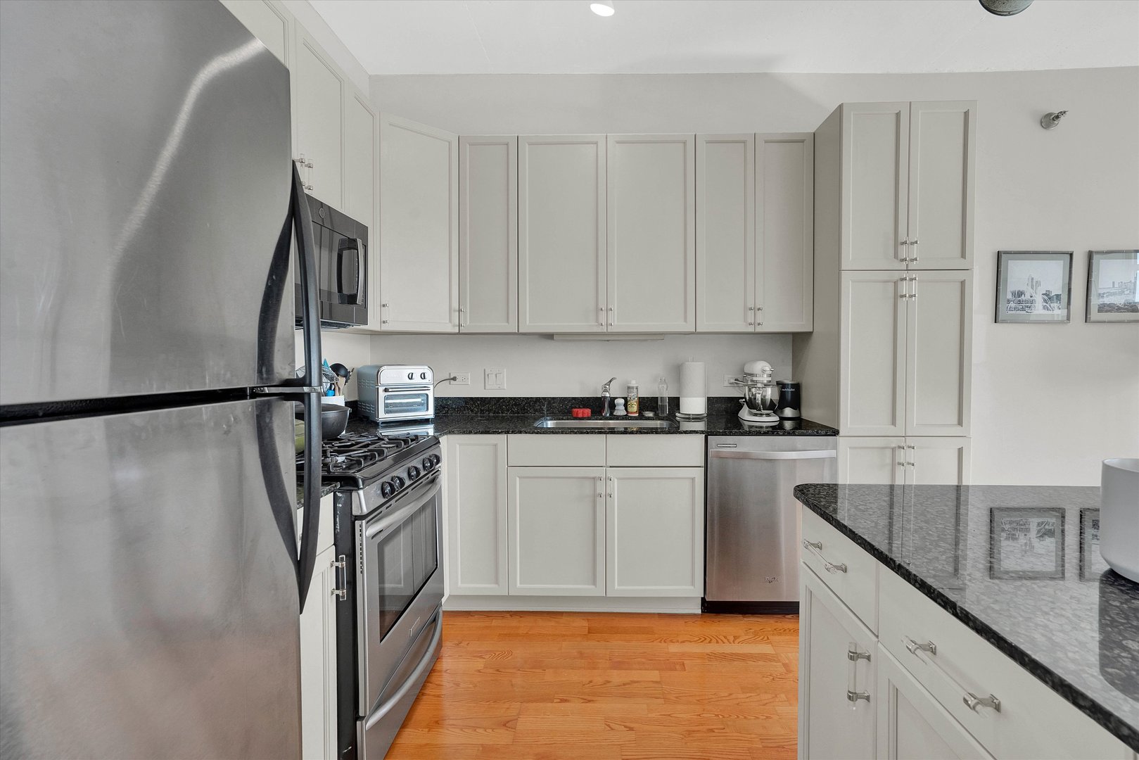 909 West Washington Boulevard, Unit 1002 Chicago, IL 60607 - Photo 5 of 15 a kitchen with stainless steel appliances granite countertop a refrigerator sink and white cabinets