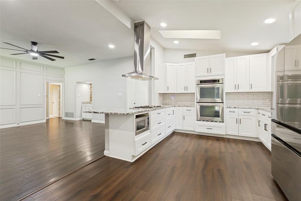 3010 Rambling Drive Dallas, TX 75228 - Photo 11 of 25 Gourmet kitchen with white cabinetry, stainless steel appliances, and a central island with a built-in microwave