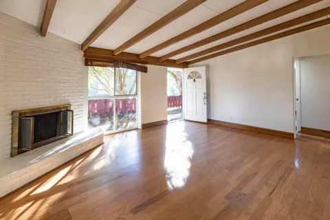an empty room with wooden floor fireplace and windows
