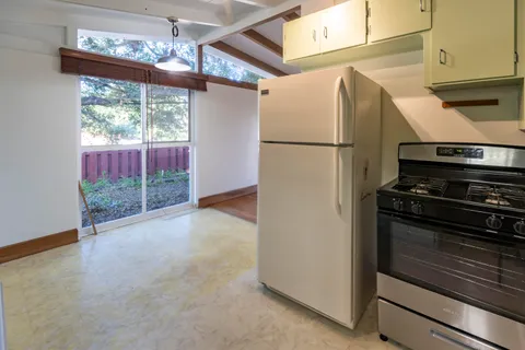 a view of a kitchen with a stove wooden cabinets and a refrigerator