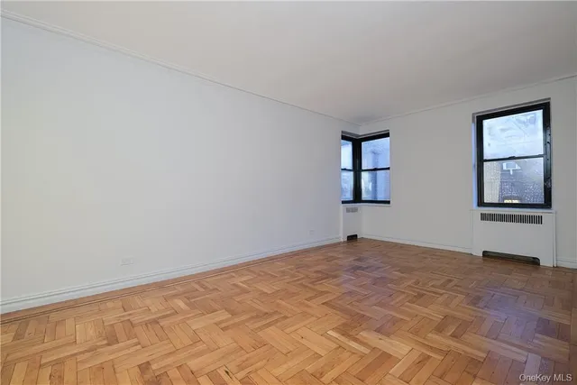 a view of an empty room with window and wooden floor