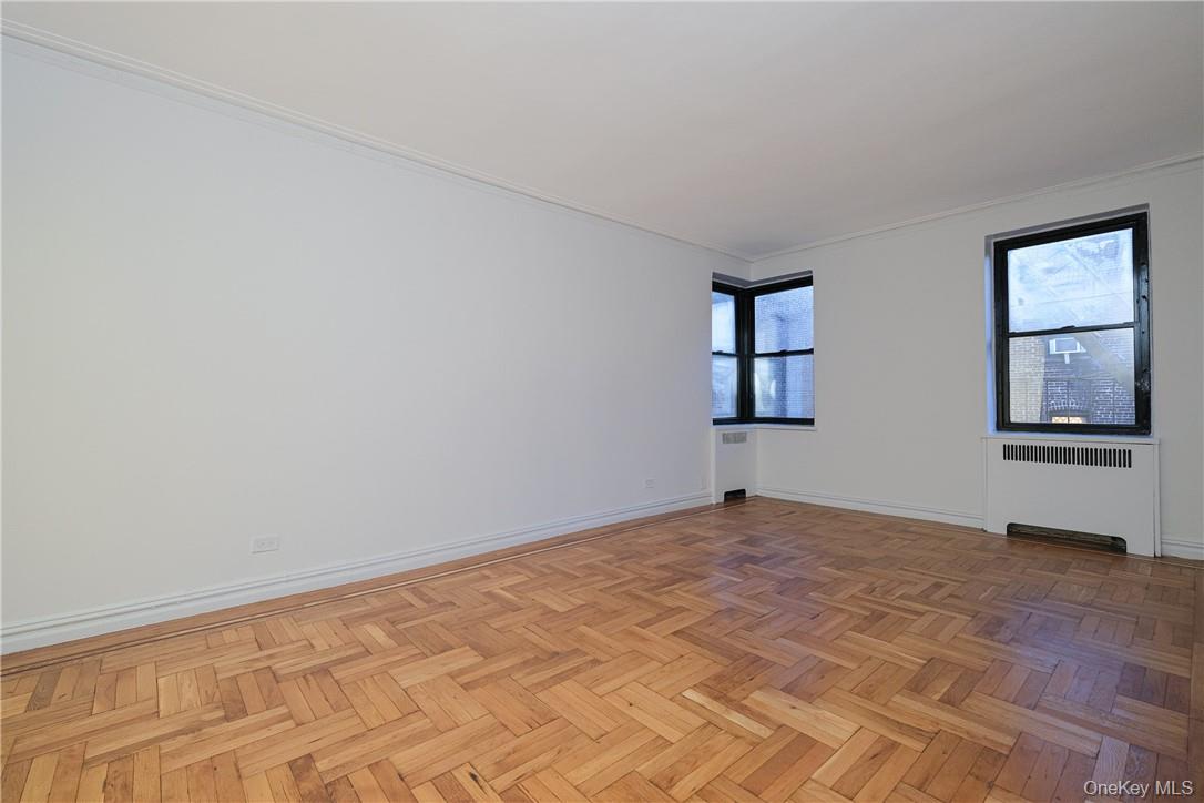 a view of an empty room with window and wooden floor