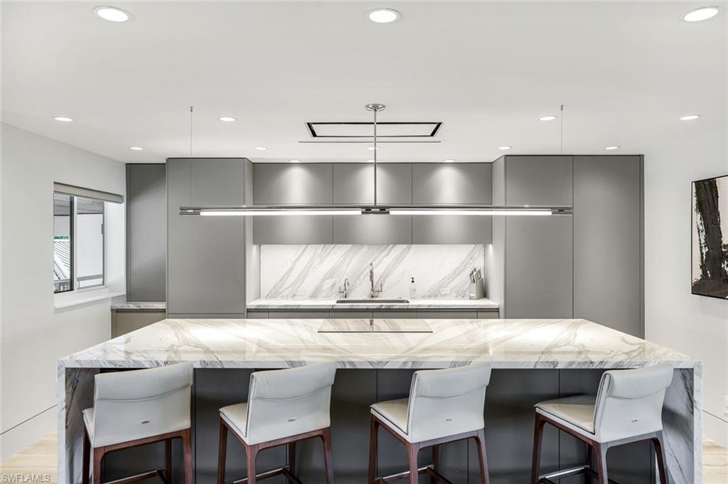 295 5th Avenue South Naples, FL 34102 - Photo 6 of 29 a kitchen with granite countertop a table chairs stainless steel appliances and cabinets