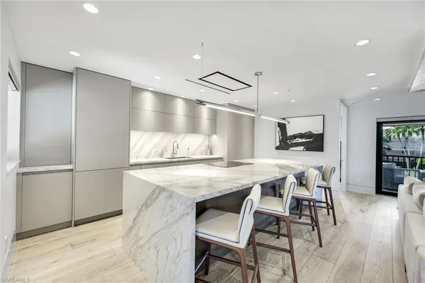 a kitchen with stainless steel appliances kitchen island granite countertop a refrigerator a stove and white cabinets with wooden floor