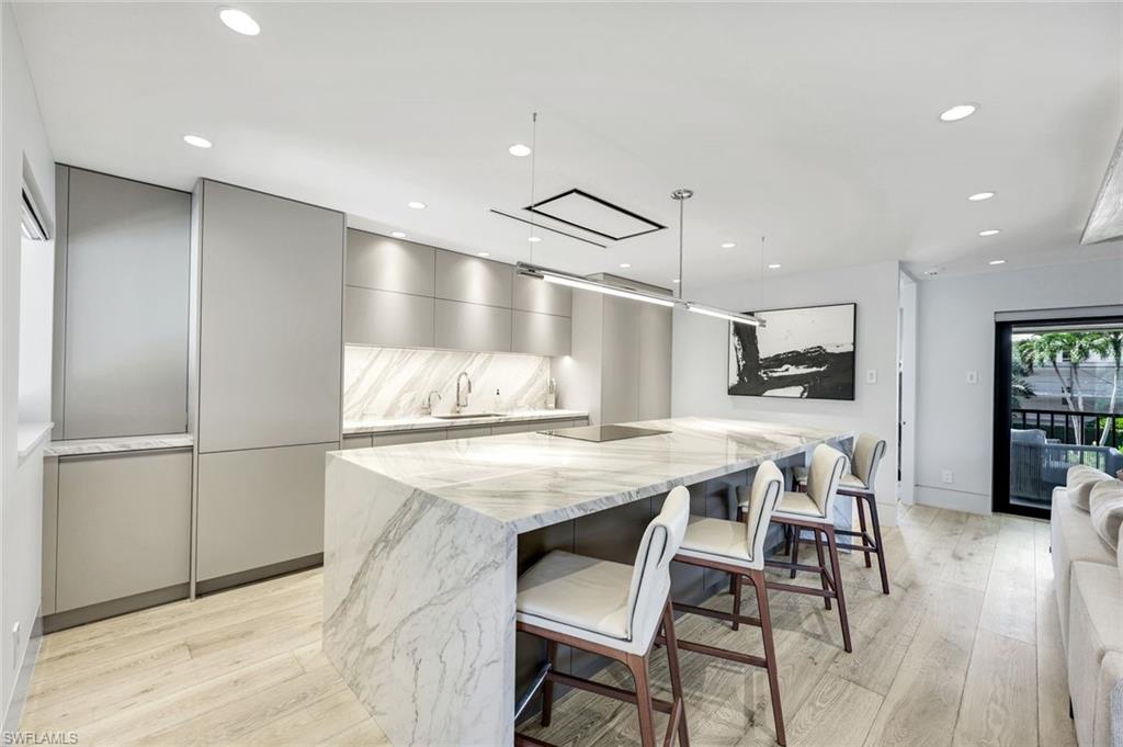 295 5th Avenue South Naples, FL 34102 - Photo 7 of 29 a kitchen with stainless steel appliances kitchen island granite countertop a refrigerator a stove and white cabinets with wooden floor