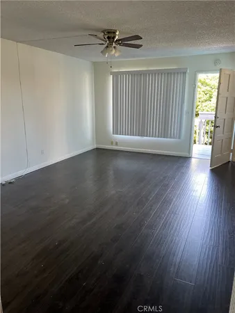 an empty room with wooden floor chandelier fan and windows