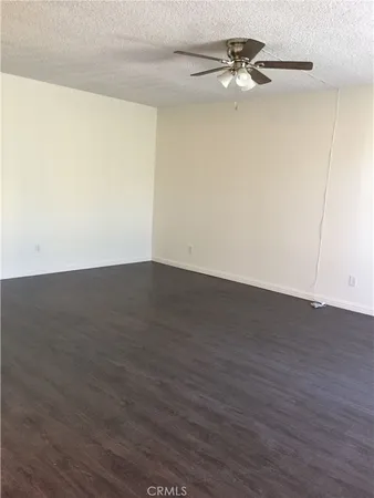 an empty room with wooden floor ceiling fan and windows