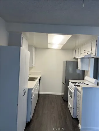 a kitchen with stainless steel appliances a white stove top oven a sink and dishwasher