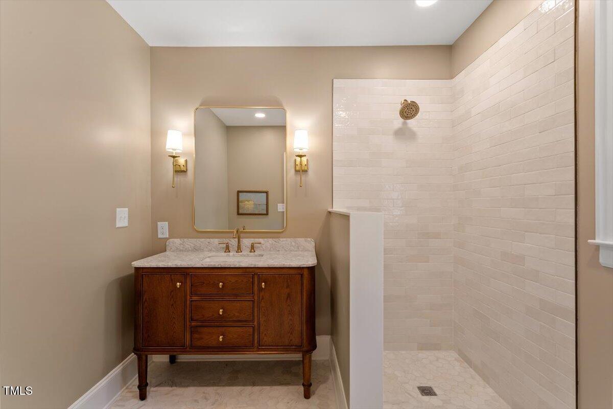 5212 Theys Road Raleigh, NC 27606 - Photo 19 of 56 a bathroom with a granite countertop sink a mirror and a shower