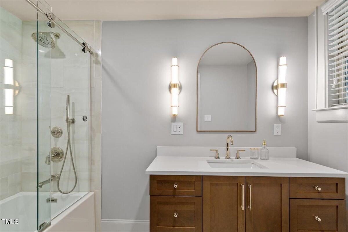 5212 Theys Road Raleigh, NC 27606 - Photo 33 of 56 a bathroom with a granite countertop sink mirror and a shower