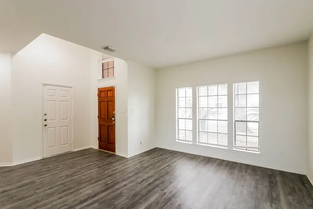 a view of a kitchen and an empty room with wooden floor kitchen view