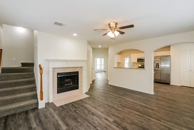 an empty room with wooden floor chandelier fan and windows