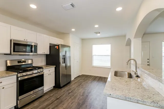a kitchen with kitchen island stainless steel appliances a sink stove and refrigerator