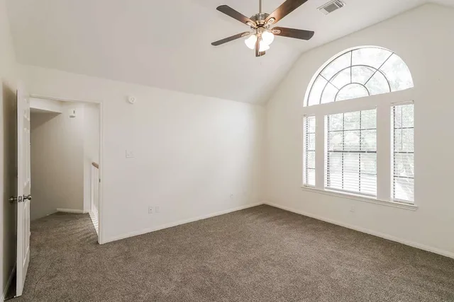 a view of empty room with window and ceiling fan