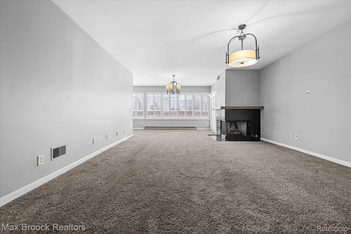 969 GreenView Court, Unit 42 Rochester, MI 48307 - Photo 16 of 41 Unfurnished living room featuring a chandelier, a fireplace, carpet flooring, and a baseboard radiator