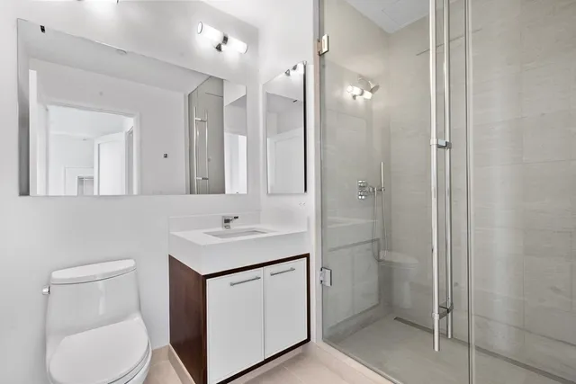 a bathroom with a sink toilet vanity and shower
