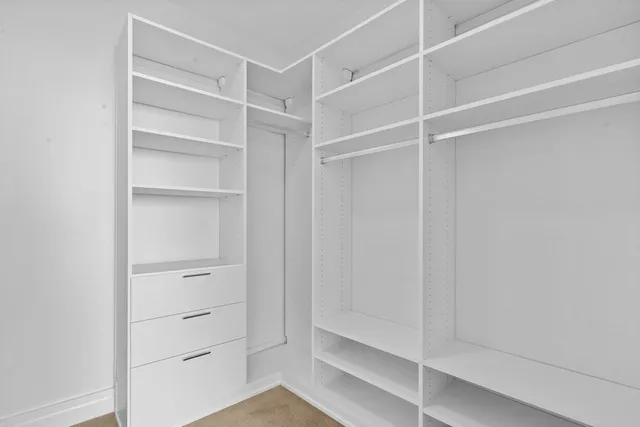 a view of walk in closet with empty racks