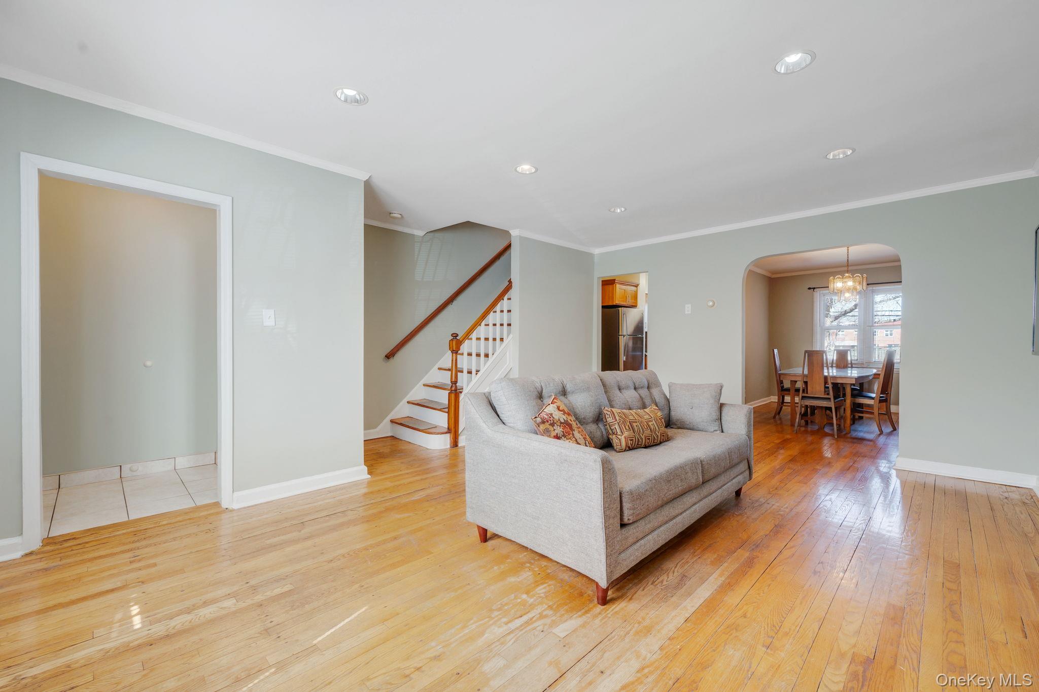 148-07 61st Road Queens, NY 11367 - Photo 5 of 21 Living area featuring arched walkways, light wood finished floors, ornamental molding, and recessed lighting
