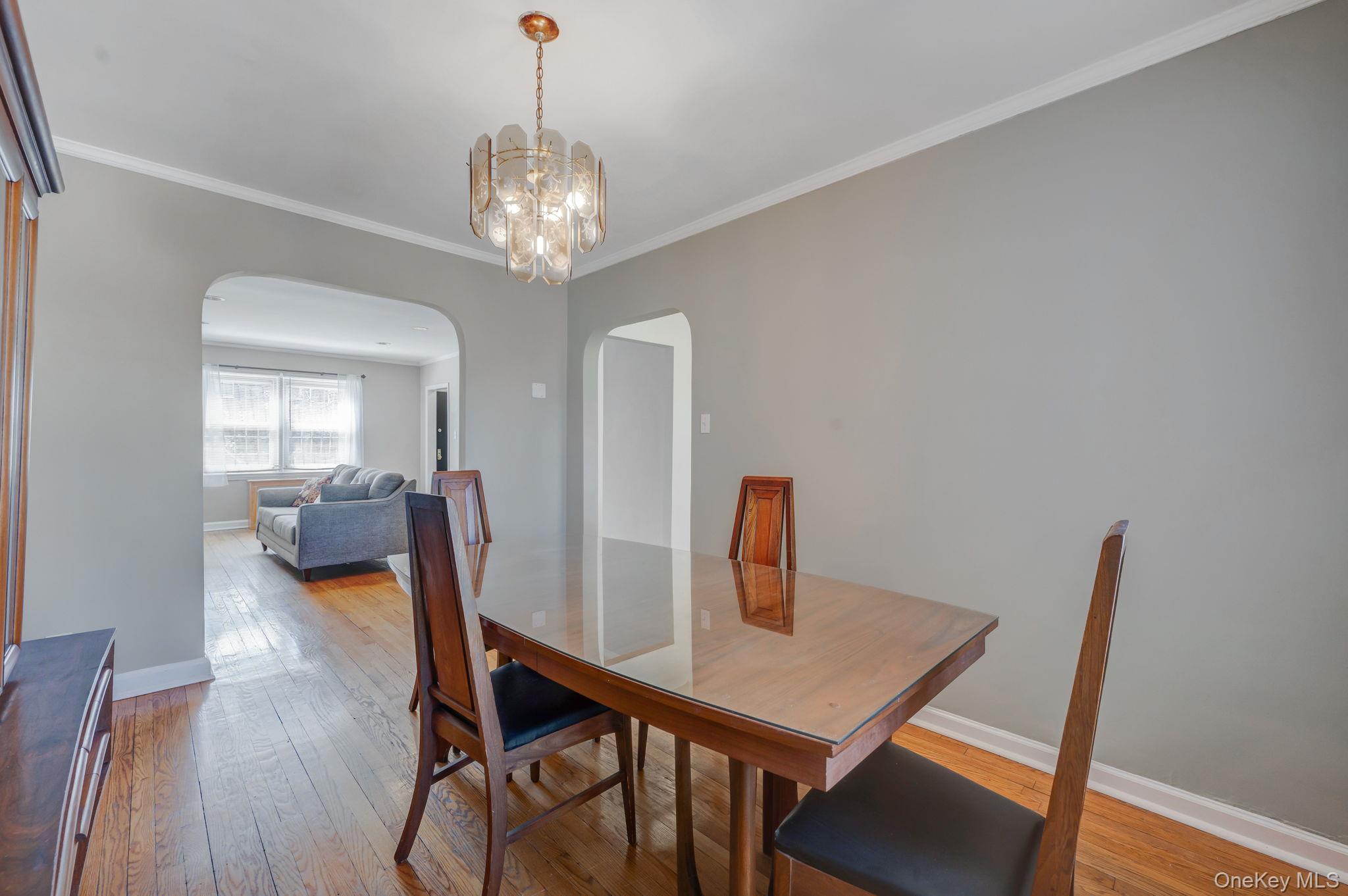 148-07 61st Road Queens, NY 11367 - Photo 8 of 21 Dining space with a chandelier, light wood-type flooring, ornamental molding, and arched walkways