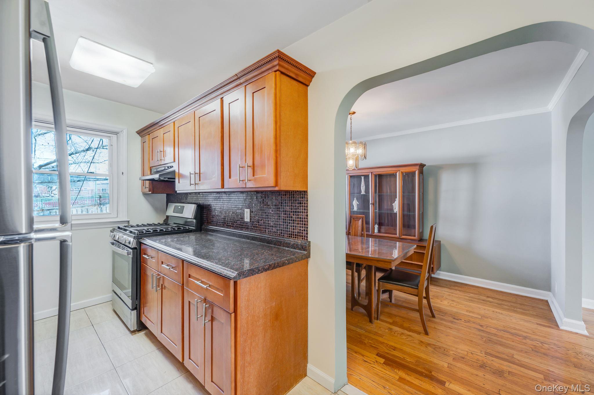 148-07 61st Road Queens, NY 11367 - Photo 10 of 21 Kitchen featuring stainless steel appliances, arched walkways, wood finish cabinetry, and backsplash