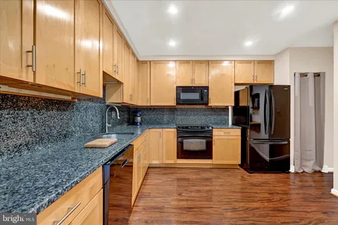a kitchen with stainless steel appliances granite countertop a refrigerator a stove and a sink