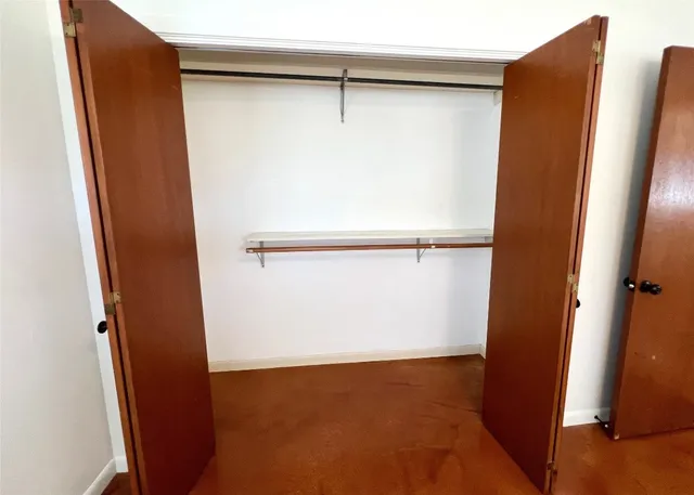 a view of an empty room with wooden floor and a ceiling fan
